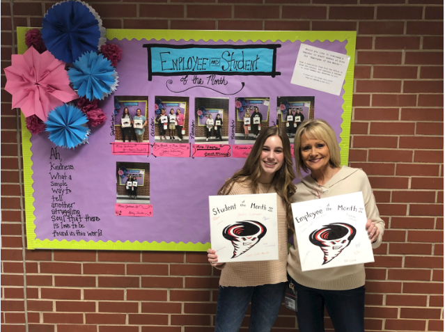 Student and teacher standing in front of a bulletin board with their awards.