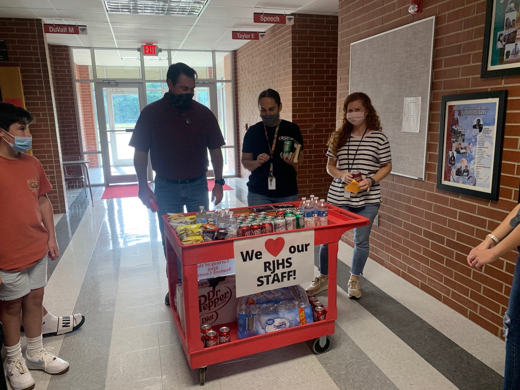 Teachers choose treats off of a red cart that has a sign that reads "We heart our RJHS Staff!"