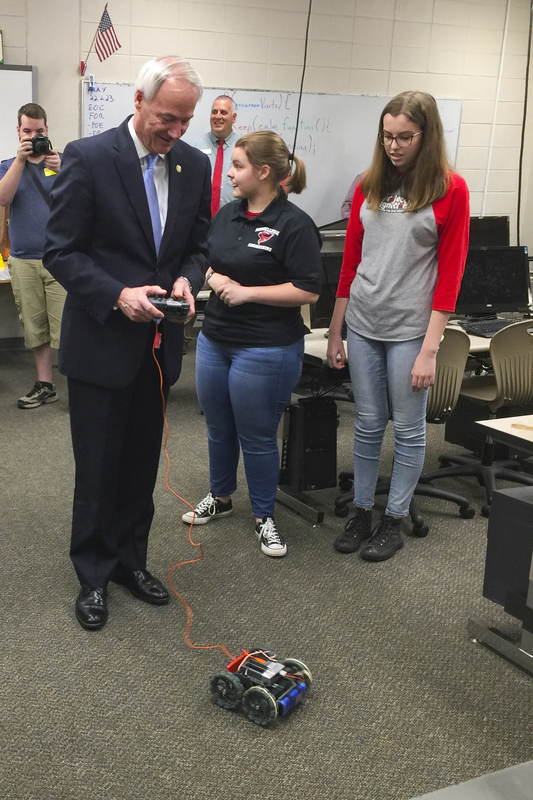 Governor Hutchinson using engineering robot while RHS engineering students look on